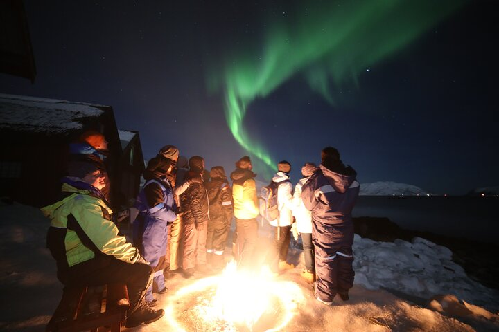 Gather around the warm glow of a fire as the Northern Lights dance overhead creating unforgettable memories in the stunning landscape of Tromso Norway. Capture the magic together!