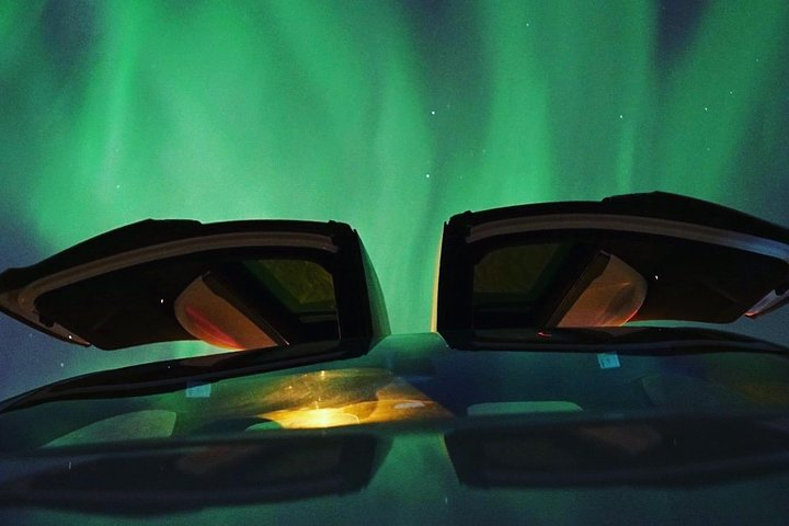 Experience the stunning Northern Lights from the comfort of a Tesla surrounded by Tromso’s breathtaking night sky blending nature and innovation for an unforgettable adventure.