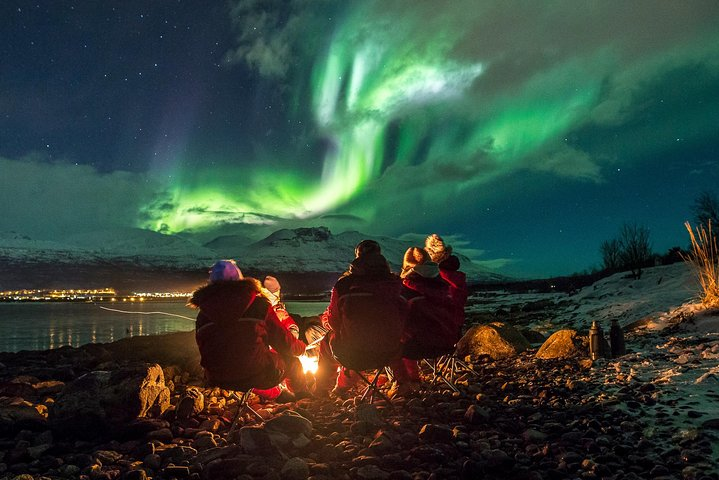 Experience the stunning dance of the Northern Lights while gathered around a cozy fire with friends creating unforgettable memories in the breathtaking Arctic landscape. Perfect for capturing that magical moment!