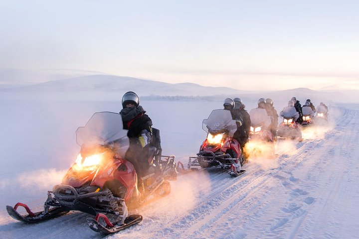 Experience the serene beauty of Finnish Lapland on a snowmobile traversing snowy landscapes and frozen lakes while enjoying a guided adventure filled with exploration and discovery.