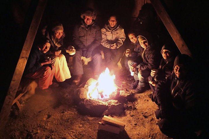 Gather around a crackling campfire after a night of snowshoeing in Tromsø sharing stories and laughter while enjoying the beauty of the Arctic landscape. Experience winter wonder and camaraderie.