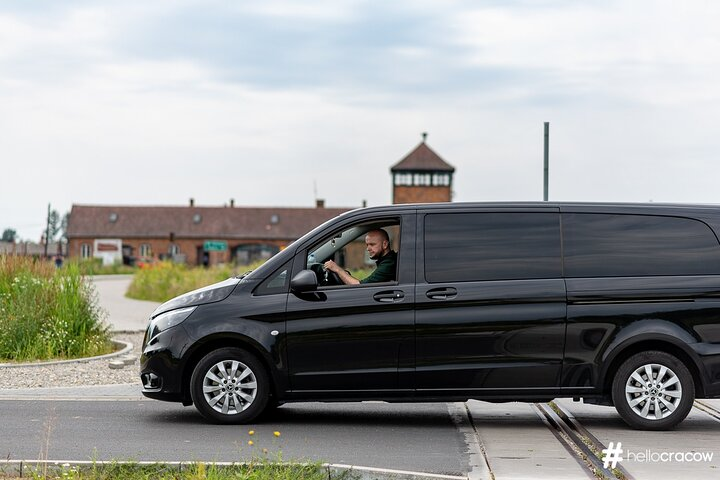 The most common means of transportation for a trip limited to 15 people, a van. The entrance gate to the Birkenau camp in the background.