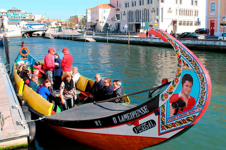 Experience the scenic beauty of Aveiro's canals aboard a traditional Moliceiro boat immersing yourself in local culture and enjoying the charming views of colorful buildings and waterways.