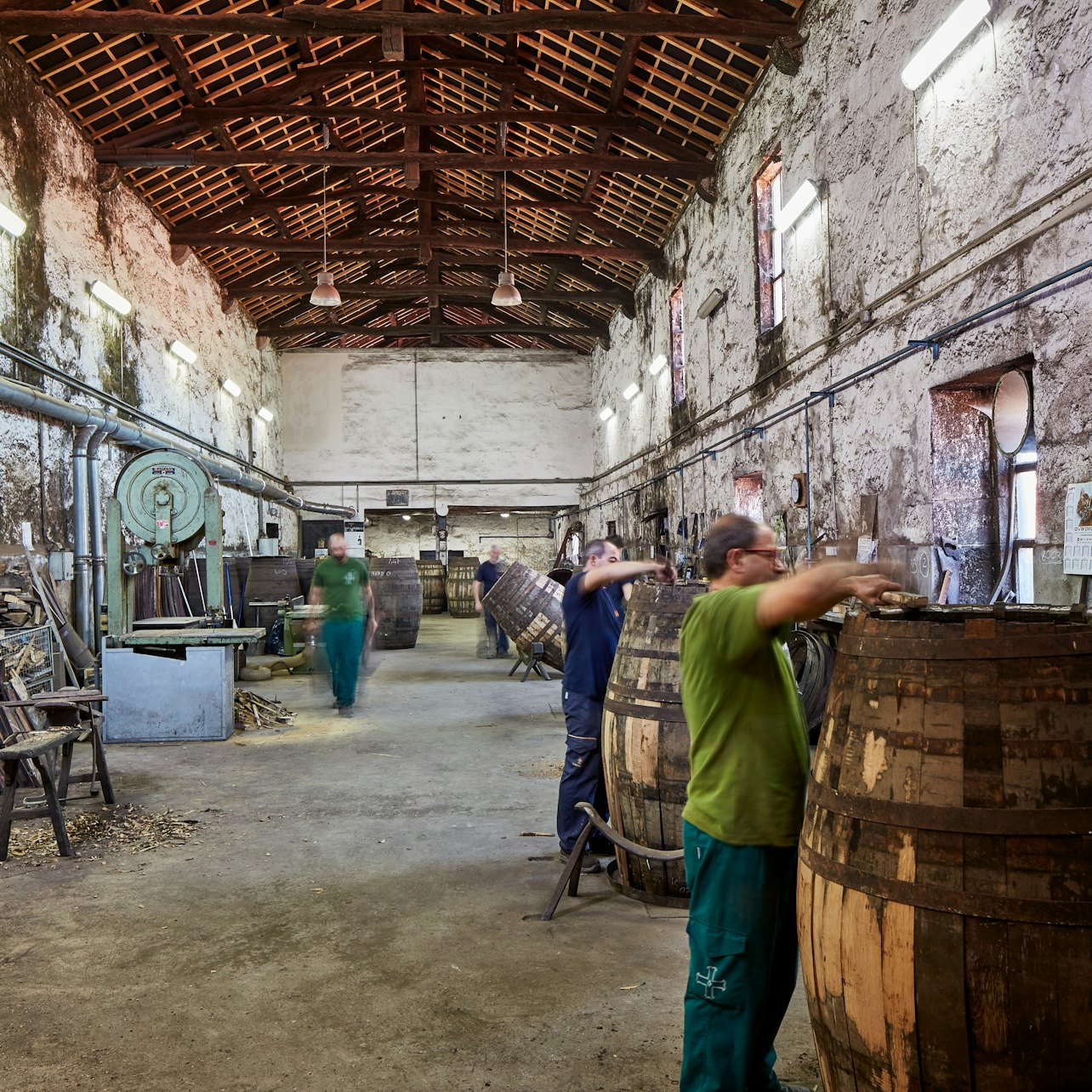 Experience the craftsmanship of Cockburn's Cellars where skilled workers meticulously handle oak barrels preserving a rich legacy while you savor exceptional Port wines in Porto.