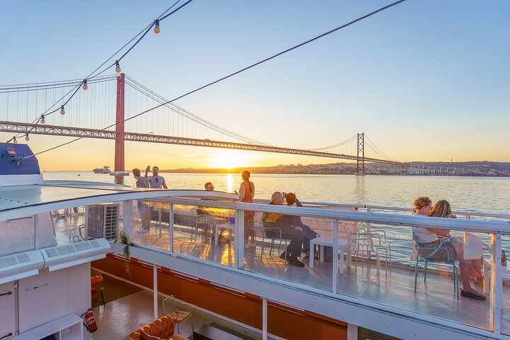 Experience the stunning sunset over the Tagus River while savoring wine and snacks all set against the iconic backdrop of Lisbon's bridge and historic skyline. A perfect evening awaits!