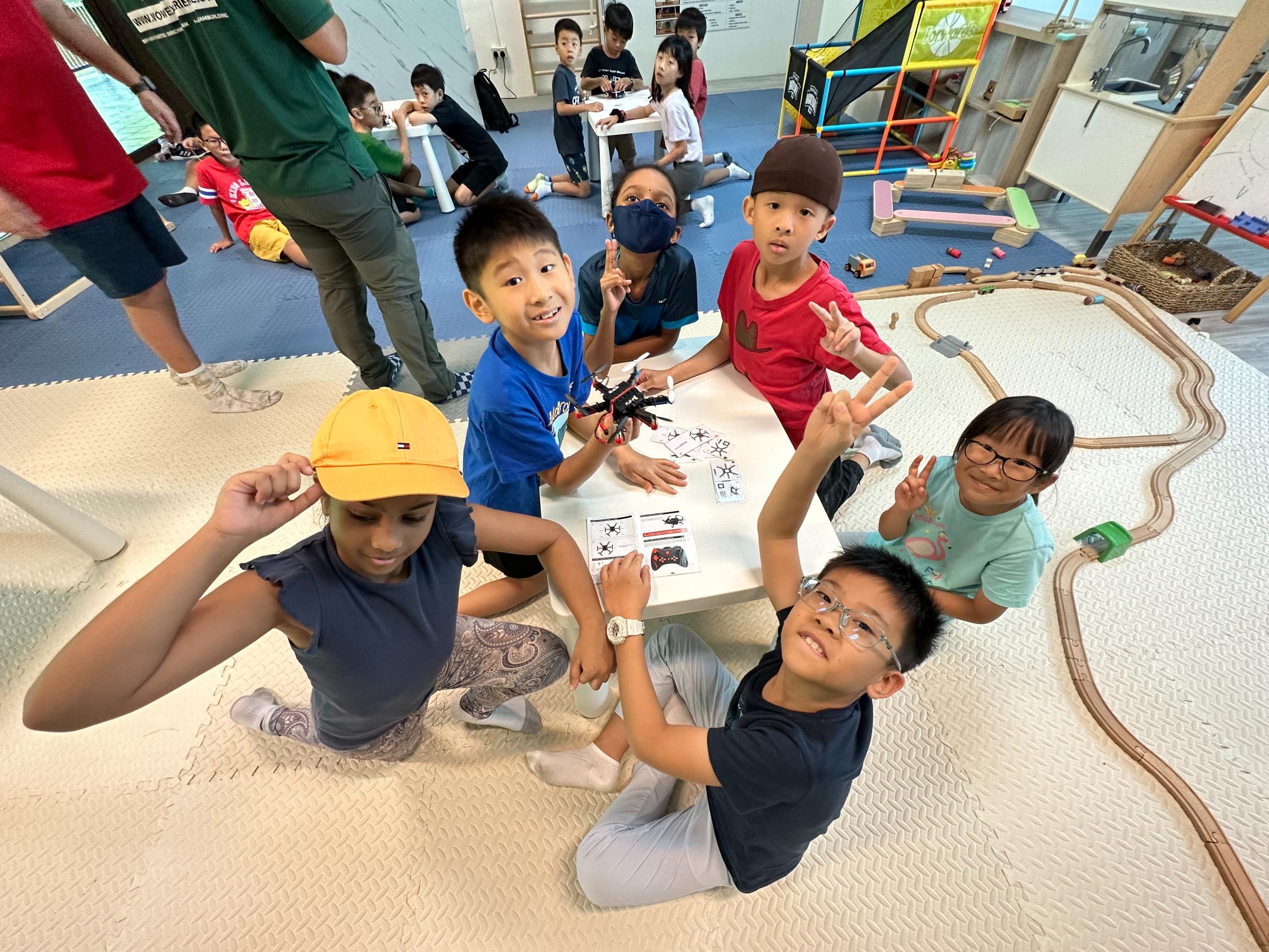 Children eagerly engage in building drones sharing laughter and creativity while exploring technology and engineering through hands-on learning. An exciting adventure awaits as they race their creations!