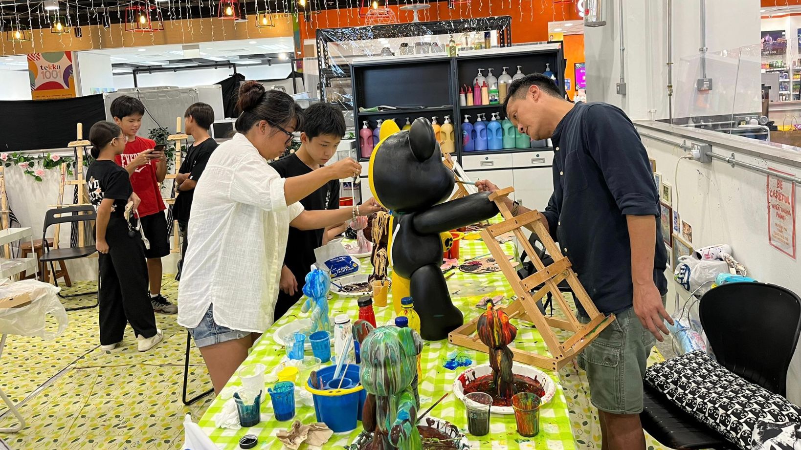 Participants creating colorful acrylic pour bears during a guided workshop session