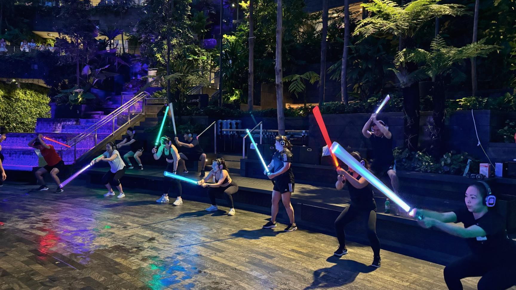 Wielding light sabers in the serene Shiseido Forest Valley participants enjoy a unique full-body workout that fuses fitness with fantasy amidst lush greenery and stunning views.