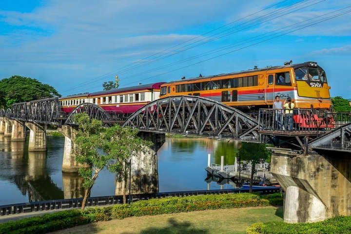 Experience the serene beauty of Kanchanaburi as a train crosses the historic Bridge on the River Kwai offering a unique glimpse into nature and history in one breathtaking location.