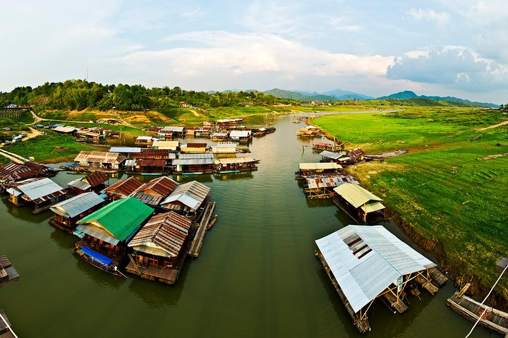 Discover the charm of riverside living with traditional floating houses surrounded by lush greenery offering an authentic glimpse into local life along the serene River Kwai.