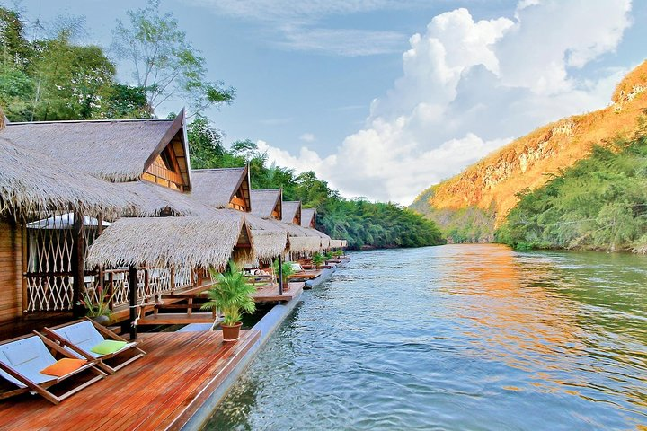 Relax by the tranquil waters of the River Kwai surrounded by lush mountains and charming floating accommodations perfect for an unforgettable experience in Thailand's rich cultural landscape.