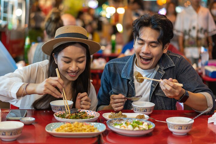 Experience the lively charm of Chinatown as you savor delicious street food with friends uncovering the rich blend of Thai and Chinese culinary delights in a bustling setting.