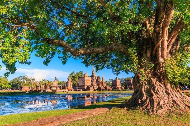 Explore the serene beauty of ancient ruins reflected in tranquil waters surrounded by lush greenery inviting you to step back in time and discover the heart of Siam.