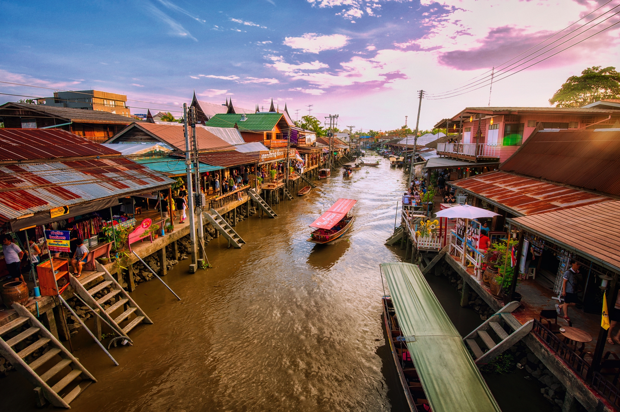 Experience the charm of local life at the Amphawa Floating Market where wooden boats glide through serene waters amid colorful wooden houses and vibrant stalls perfect for an unforgettable day.