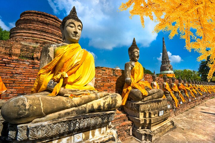 Explore the serenity of ancient temples and statues adorned in golden robes inviting travelers to experience the rich history and artistry of Ayutthaya's remarkable UNESCO World Heritage sites.