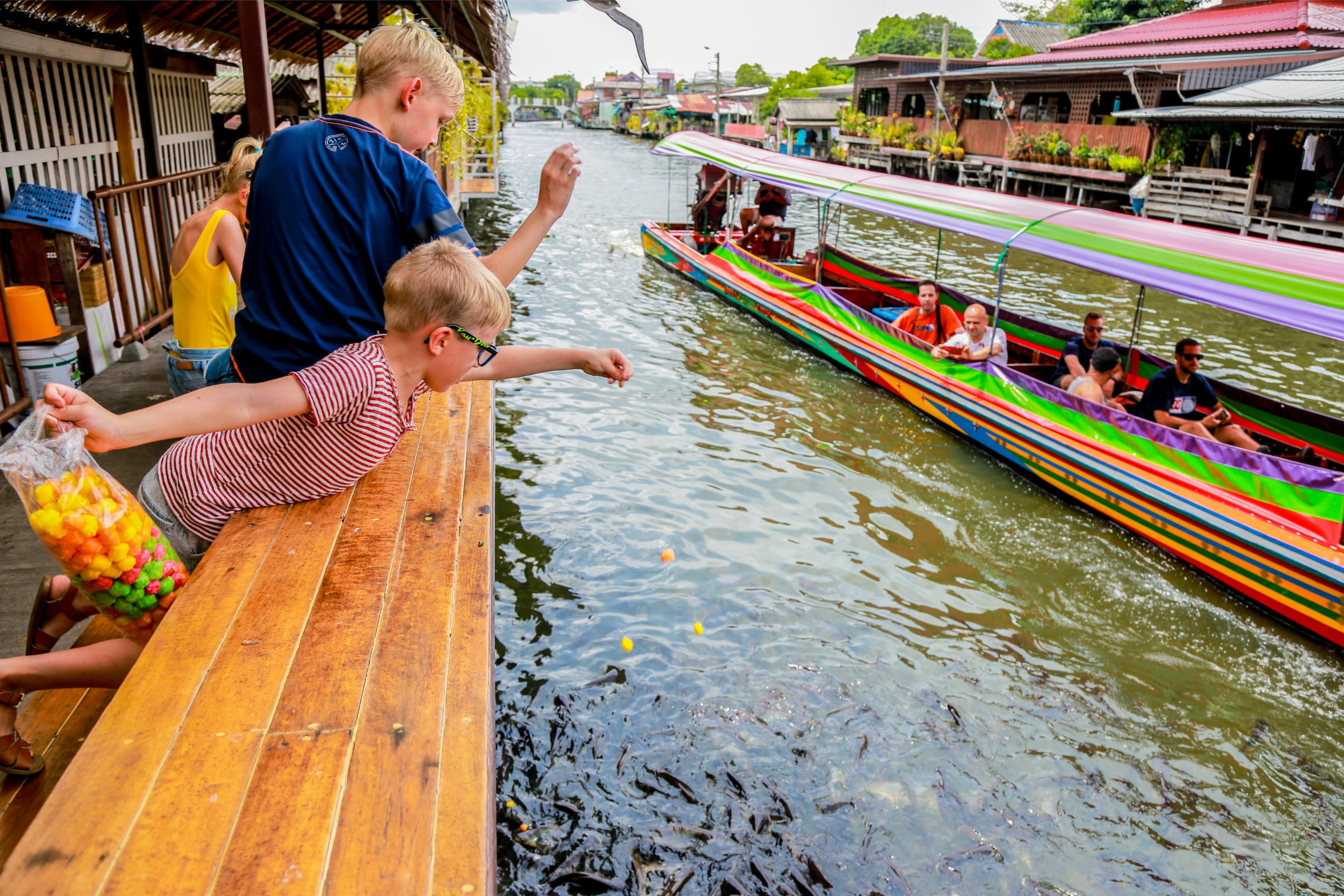 Experience the joy of tossing treats to local fish while colorful boats glide by highlighting the fun and interactive moments found along Bangkok's serene canals. A day of exploration awaits!