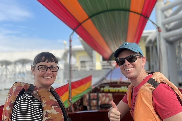 Experience the charm of Bangkok's canals aboard a long-tail boat enjoying scenic views of traditional homes and the famous Wat Arun a highlight of your travels.