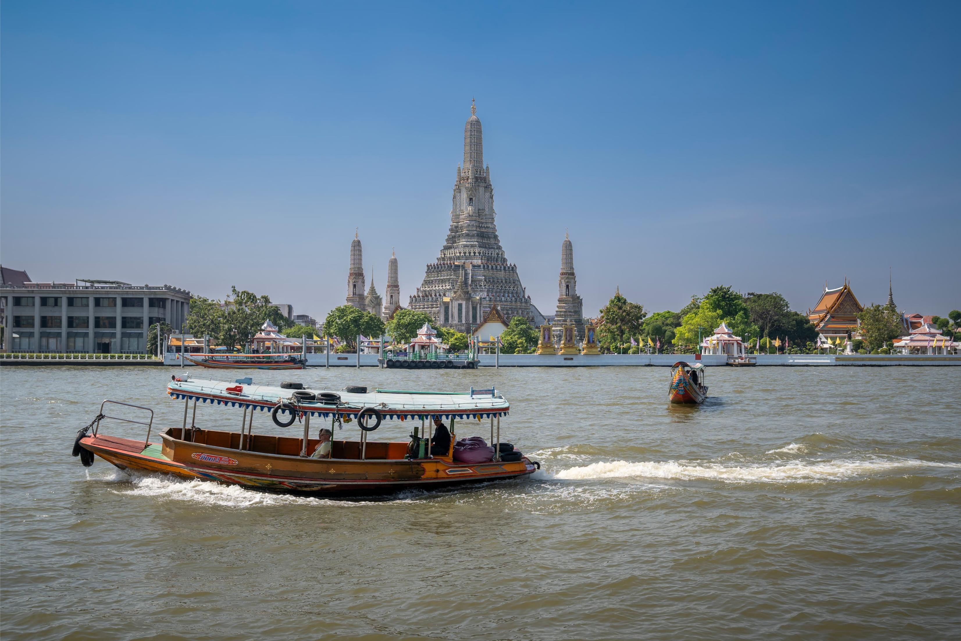 Drift along Bangkok's serene canals on a traditional longtail boat with the majestic Wat Arun rising in the background—a perfect blend of culture and scenic beauty to explore.