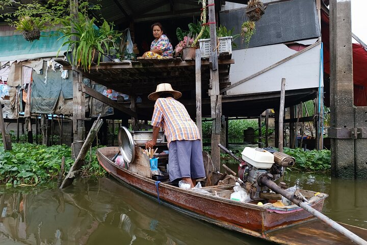 Experience the charm of Bangkok's canals as locals engage in daily life from fishing to hanging laundry all while exploring the unique waterways on traditional boats.