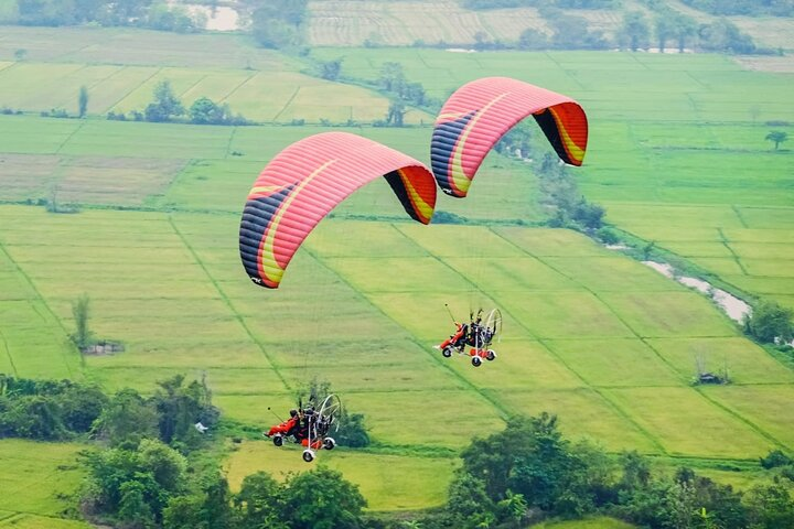 Soar above the stunning paddy fields of Chiang Mai embracing the freedom of flight and the breathtaking views of sacred temples and serene rivers during an unforgettable paramotor experience.