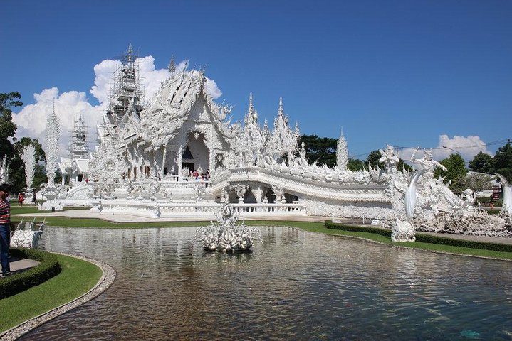 Explore the intricate design of the White Temple where shimmering white architecture meets serene water reflections inviting travelers to marvel at its unique beauty and artistry.