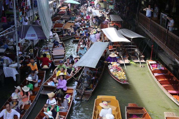 Experience the lively scene of Damnoen Saduak with colorful boats navigating the bustling canals offering a taste of local culture and a glimpse into everyday life in Thailand.