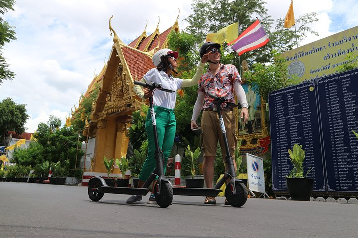 Experience the charm of Bangkok as you glide on an e-scooter discovering hidden temples bustling food markets and stunning architecture while indulging in delicious street food.