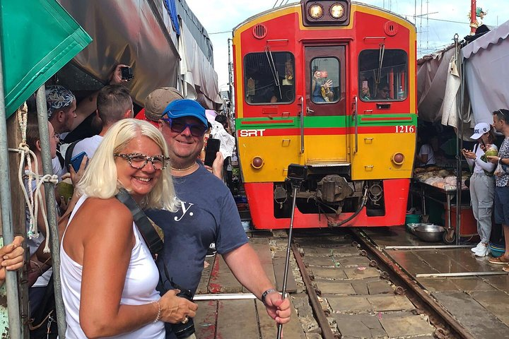 Experience the unique sight of a train passing through a bustling market as vendors quickly retract their stalls. Witness the unexpected charm of daily life in Thailand.