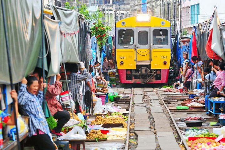 Experience the unique hustle of Maeklong Railway Market where vendors quickly move goods as a train approaches showcasing a blend of traditional Thai culture and daily life.