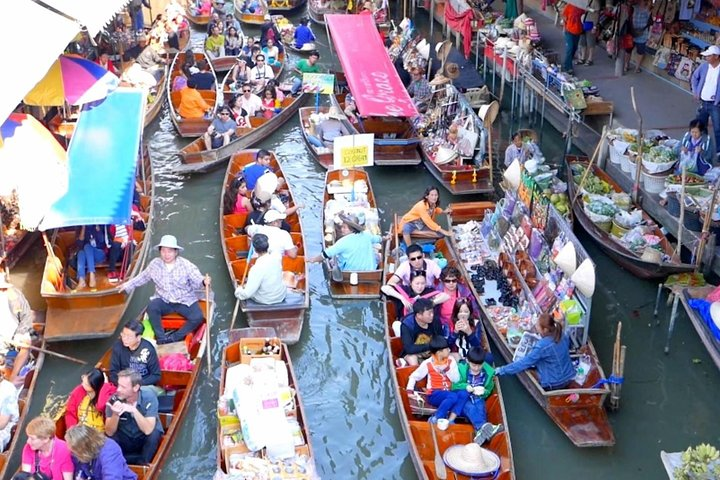 Immerse yourself in a lively scene of boats bustling with merchants selling fresh produce and delicious street food showcasing the heart of rural Thai culture along picturesque canal waterways.