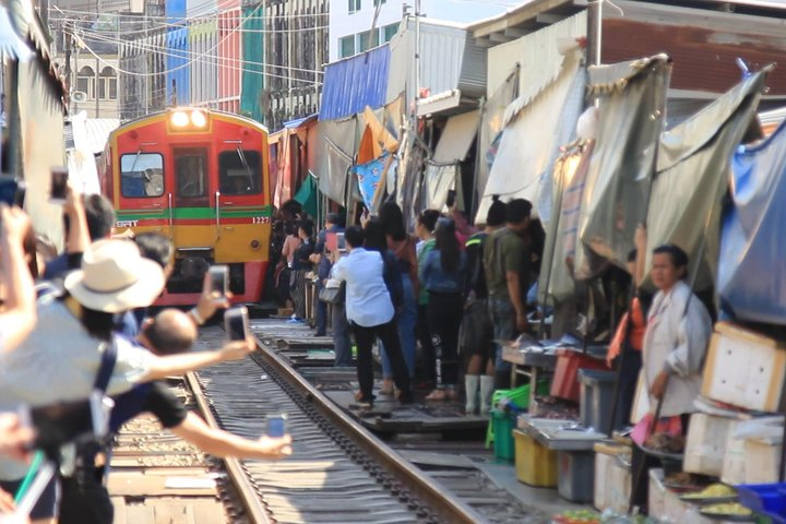 Witness the unique experience of a train gliding through bustling stalls at the Folding Umbrella Market where fresh produce meets lively vendors an unforgettable highlight for every traveler.