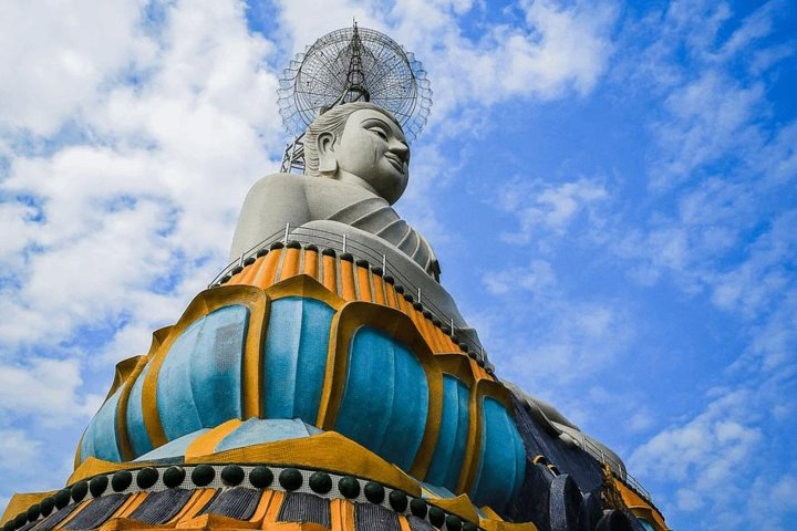 Discover the serene beauty of Ratchaburi with its stunning Buddhist statue striking against a backdrop of blue skies inviting reflection and connection to nature. Experience the essence of Thai culture.