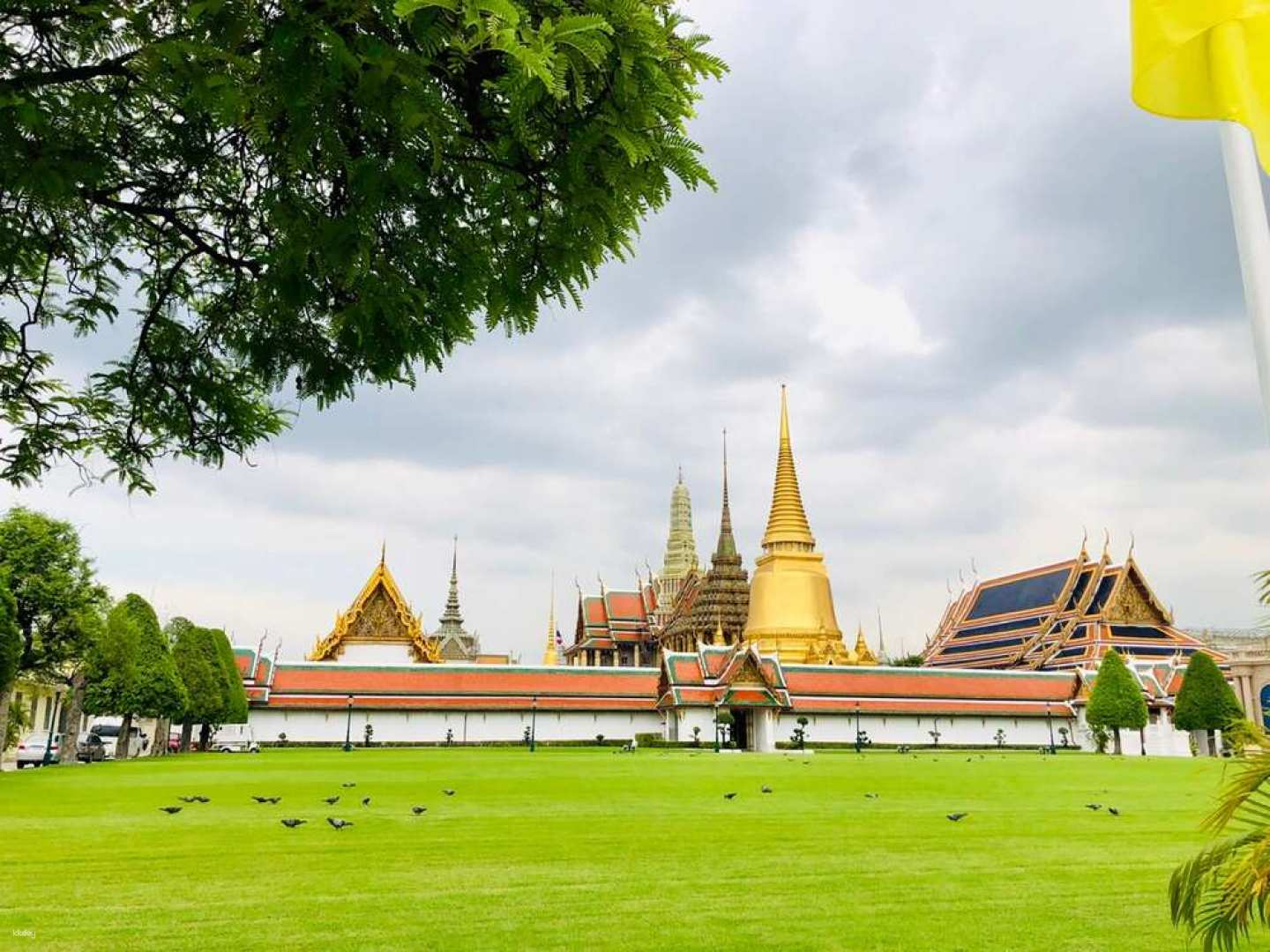 Discover the stunning architecture and rich history of the Royal Palace highlighted by the iconic Emerald Buddha all set against a lush green landscape in Bangkok.