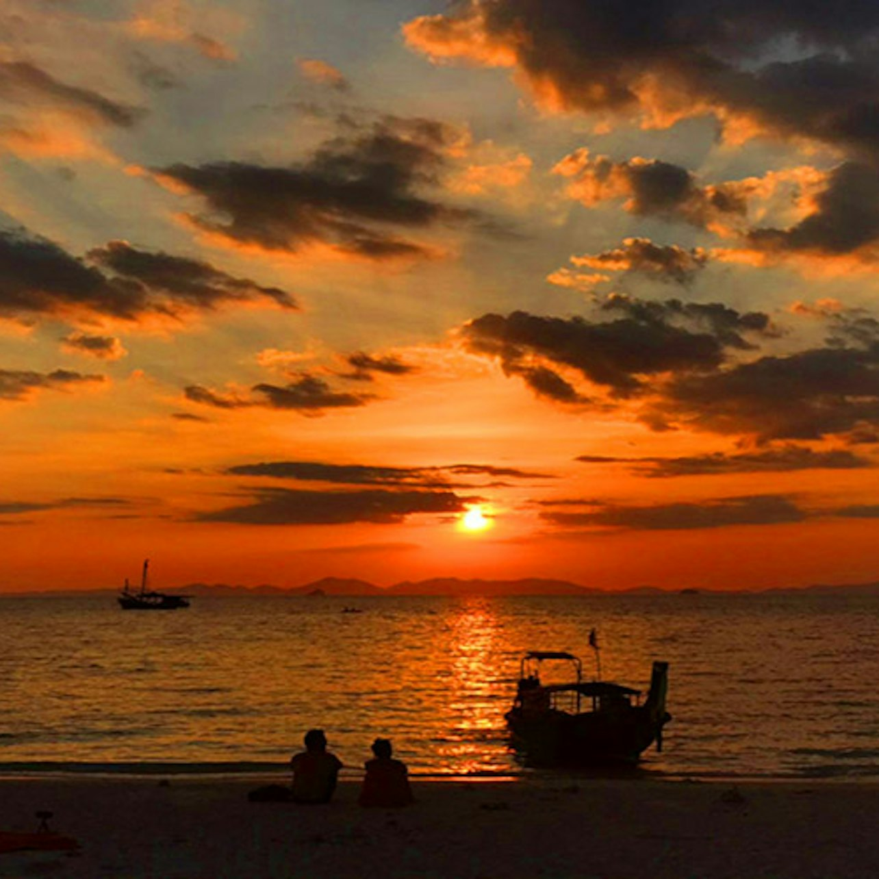 Experience the magic of Krabi’s sunset as you relax by the shore with long-tail boats silhouetted against the stunning colors of the sky inviting you to explore the sea's wonders.