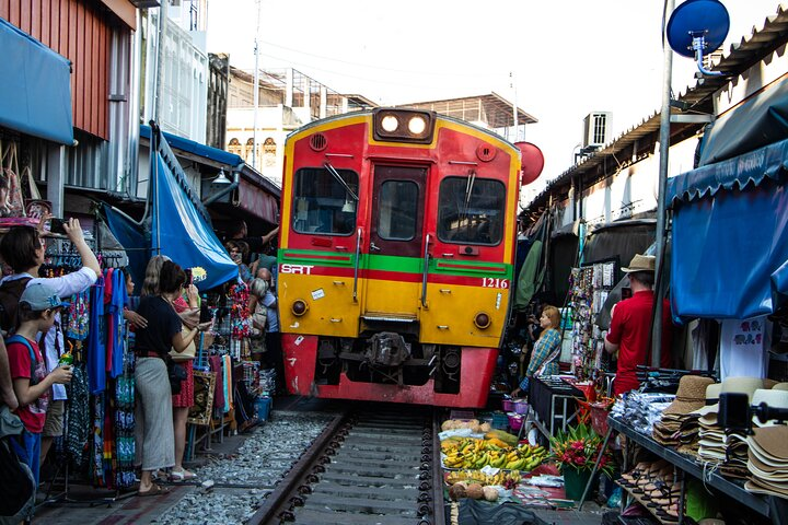 Experience the unique Meaklong Railway Market where trains glide through bustling stalls creating unforgettable moments as shop fronts and awnings seamlessly adjust for passing locomotives.