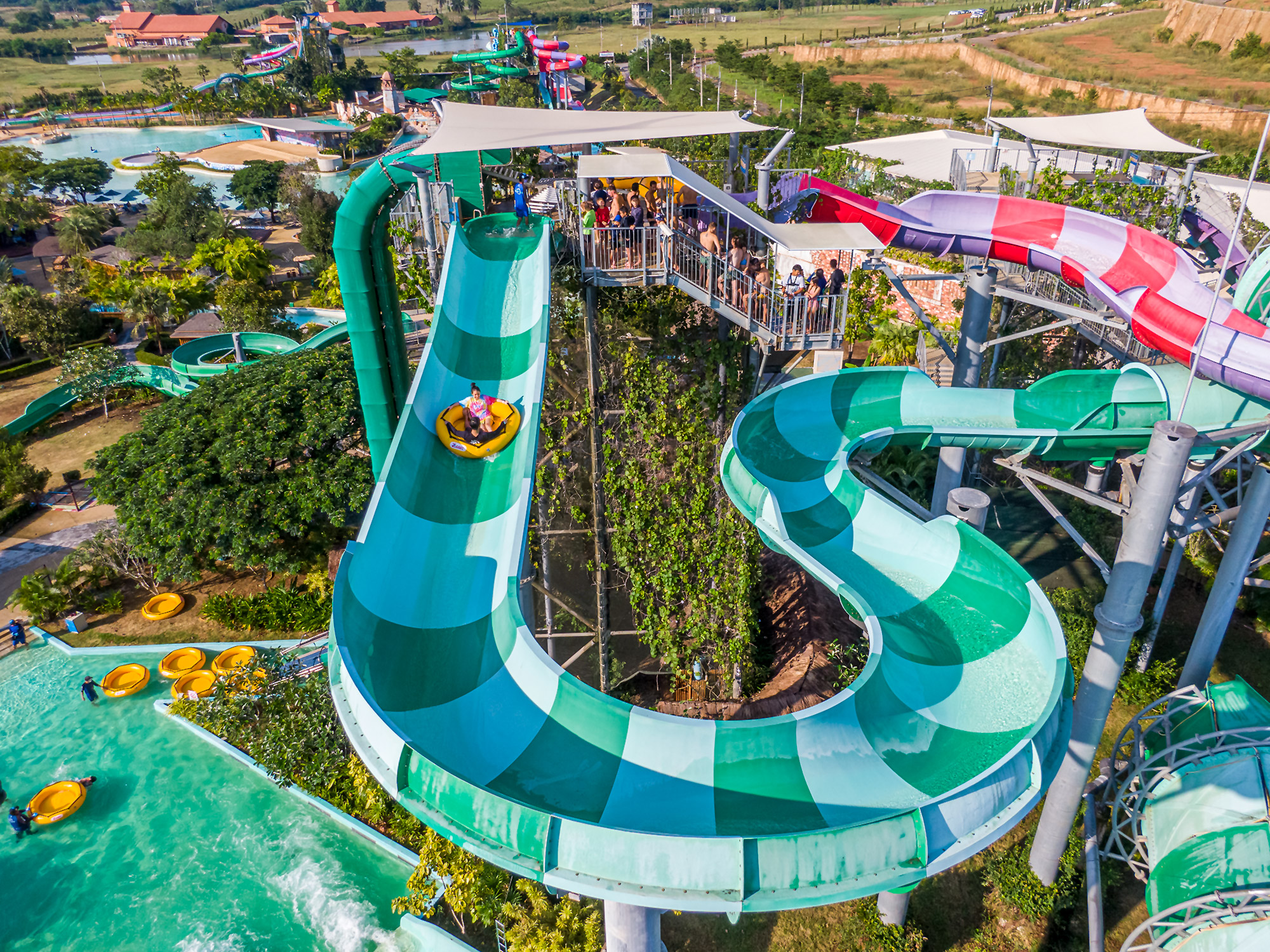 Experience the excitement of water slides winding through lush scenery with sparkling pools and stunning views of ancient structures promising a day full of exploration and fun.