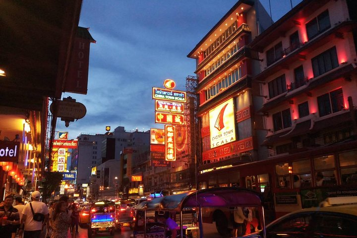 Explore the lively streets of Bangkok's China Town where tantalizing food stalls beckon and the neon lights create a unique dining experience under the twilight sky.