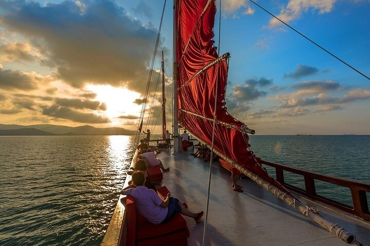 Experience the serene beauty of Koh Samui as the sun sets enjoying dinner aboard an authentic wooden yacht surrounded by picturesque views and gentle waves.