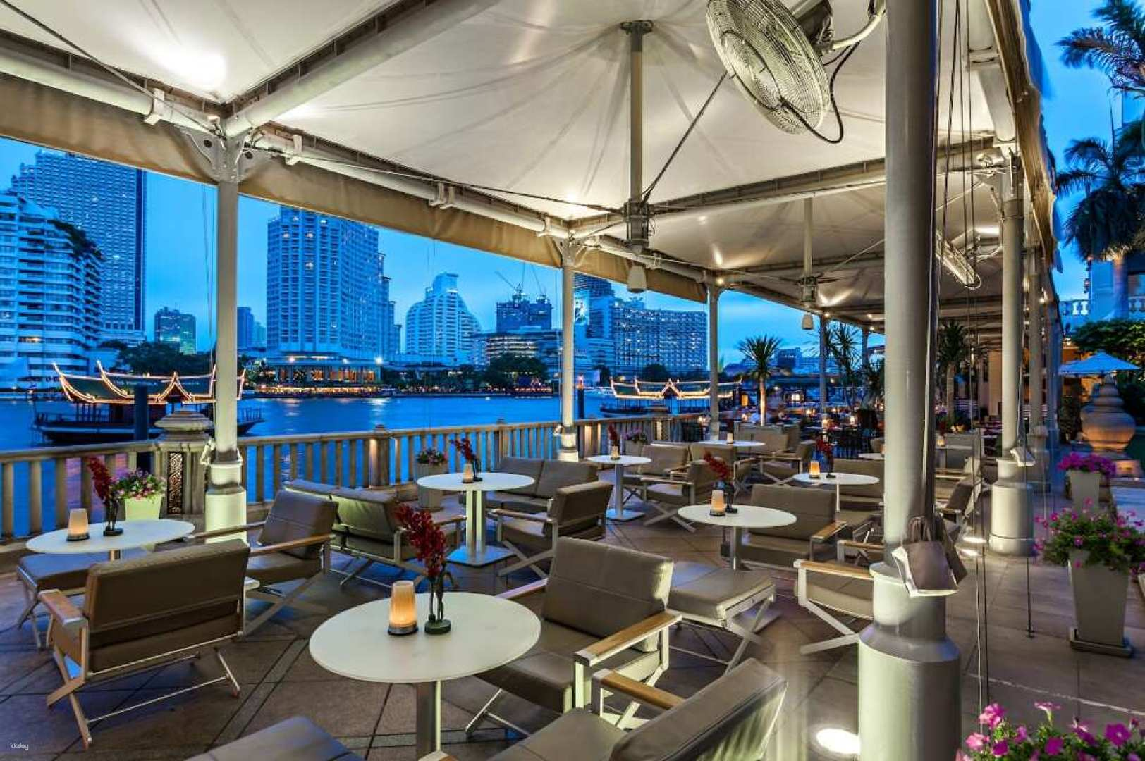 Dine riverside at the Peninsula Hotel savoring fresh Thai and international dishes while enjoying views of the city skyline creating a memorable culinary experience under the night sky.