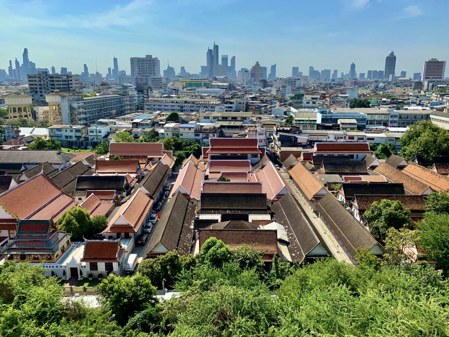 Experience the bustling charm of Bangkok as you glide through the old town in a tuk-tuk discovering hidden gems and the striking silhouette of Wat Saket against the skyline.