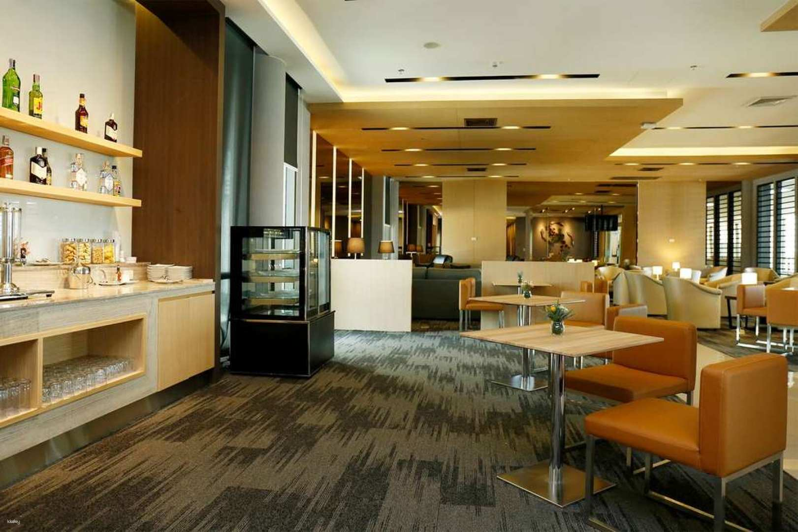 Relax in comfort before your flight at Don Mueang Airport's luxurious lounges enjoying light snacks and a view of departure monitors perfect for a seamless travel experience.