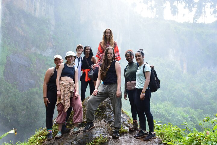 A group posing for a photo moment at the waterfall.