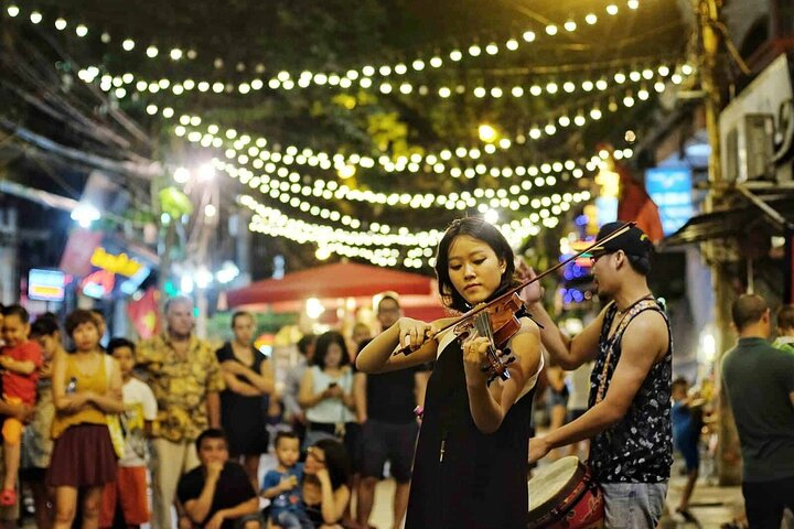 Experience the lively sounds of street performances as local musicians entertain crowds under a canopy of lights creating a magical setting perfect for making lasting memories in Hanoi.
