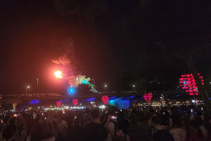 Experience the lively blend of culture and excitement as fire and water dance in the night sky celebrating the magic of Da Nang's Dragon Fire Show against a backdrop of festive lights.