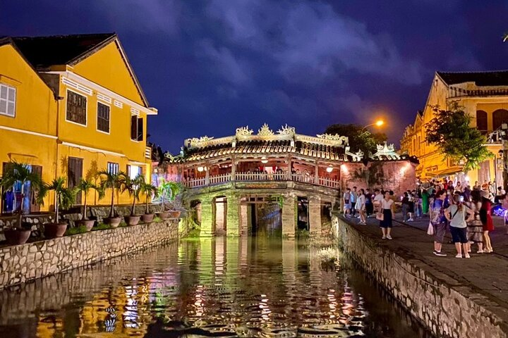 Experience the charm of Hoi An as the lanterns cast a warm glow over the ancient bridge reflecting beautifully in the water while capturing the essence of Vietnamese culture.